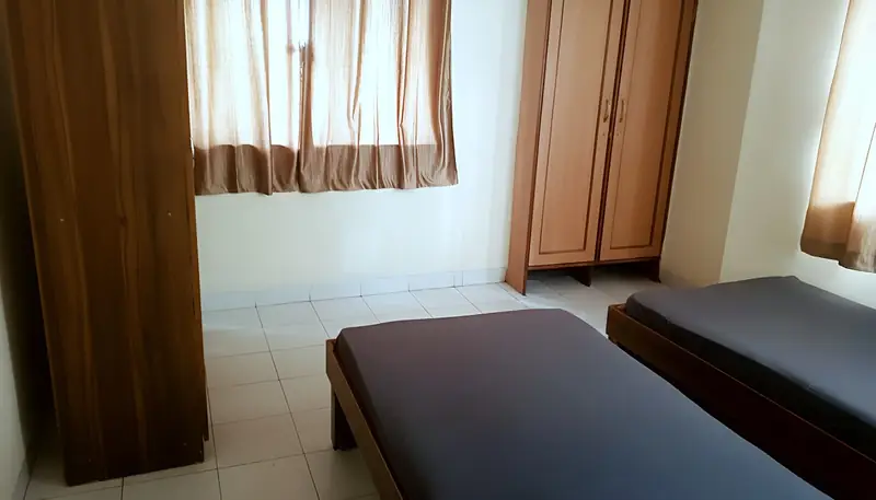 Room with two single beds, window curtains and wardrobes